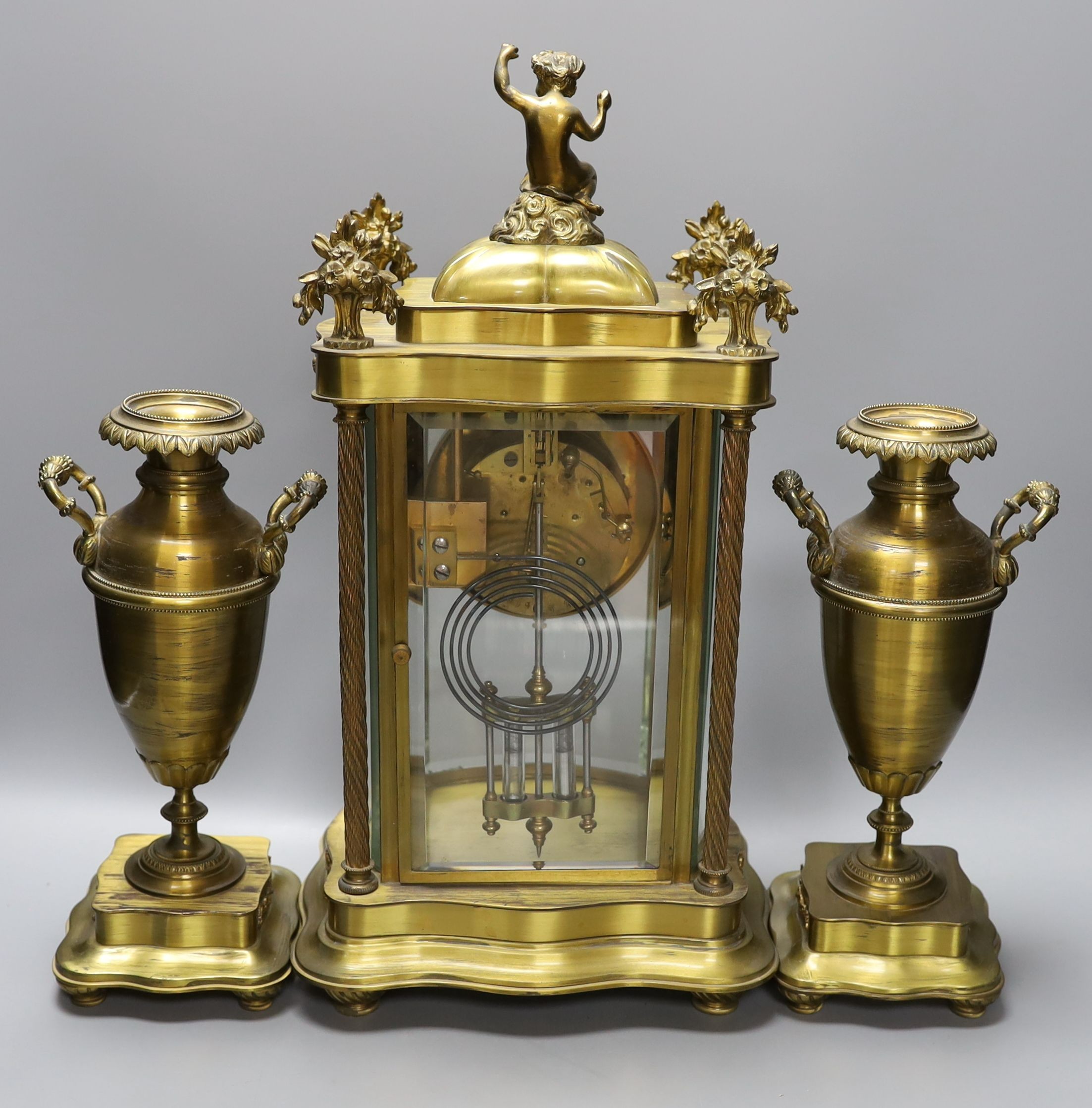 An early 20th century French brass four glass mantel clock garniture with key and pendulum, 41cm tall